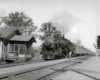 A train pulling into a train station as a man watches