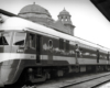 A lady walking by a train parked in a train station