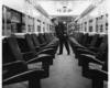 a conducter looking down the aisle on a passenger train