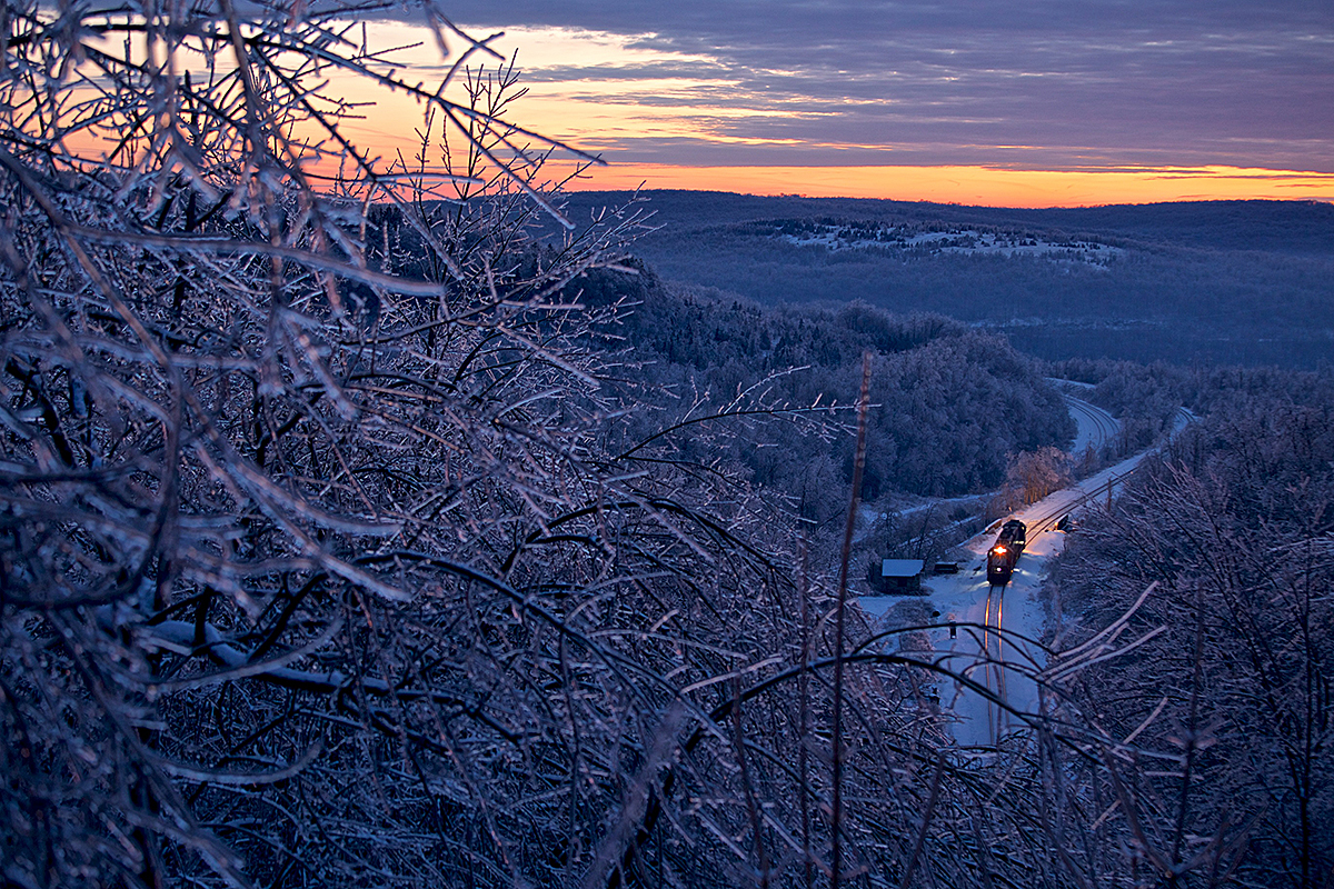 A distant, overhead, shot of a train passing through a snowy area