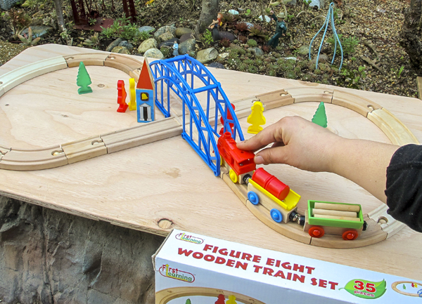 hand playing with wooden train set on table