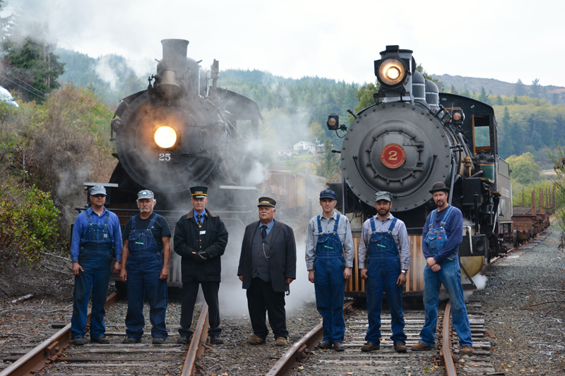 group of men in front of two steam locomotives