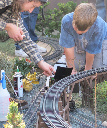 adult assisting child with live-steam locomotive