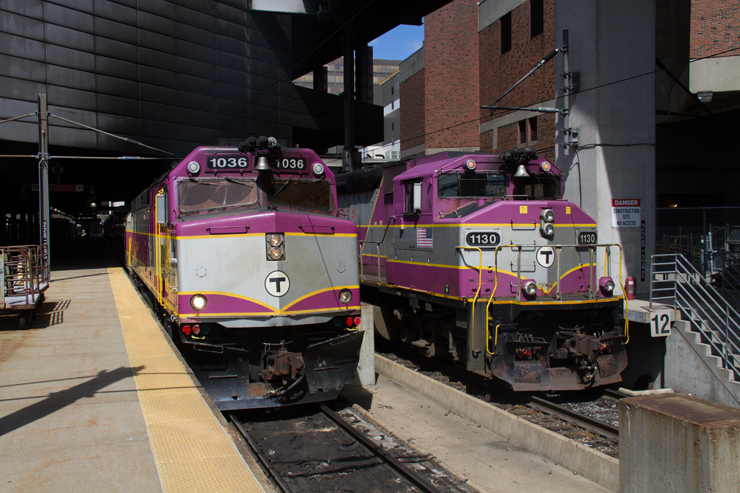 two purple and silver MBTA commuter trains in station