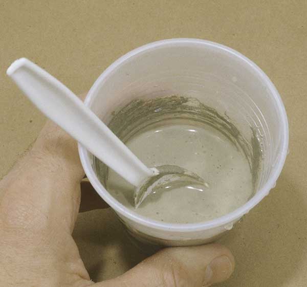 Fig. 2 Mixing the concrete. Lance filled a plastic cup about 1/3 full of powdered cement then slowly added water. 