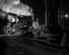 Two trains sitting on the tracks in the night