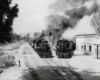 Two trains, moving side by side, leaving a station