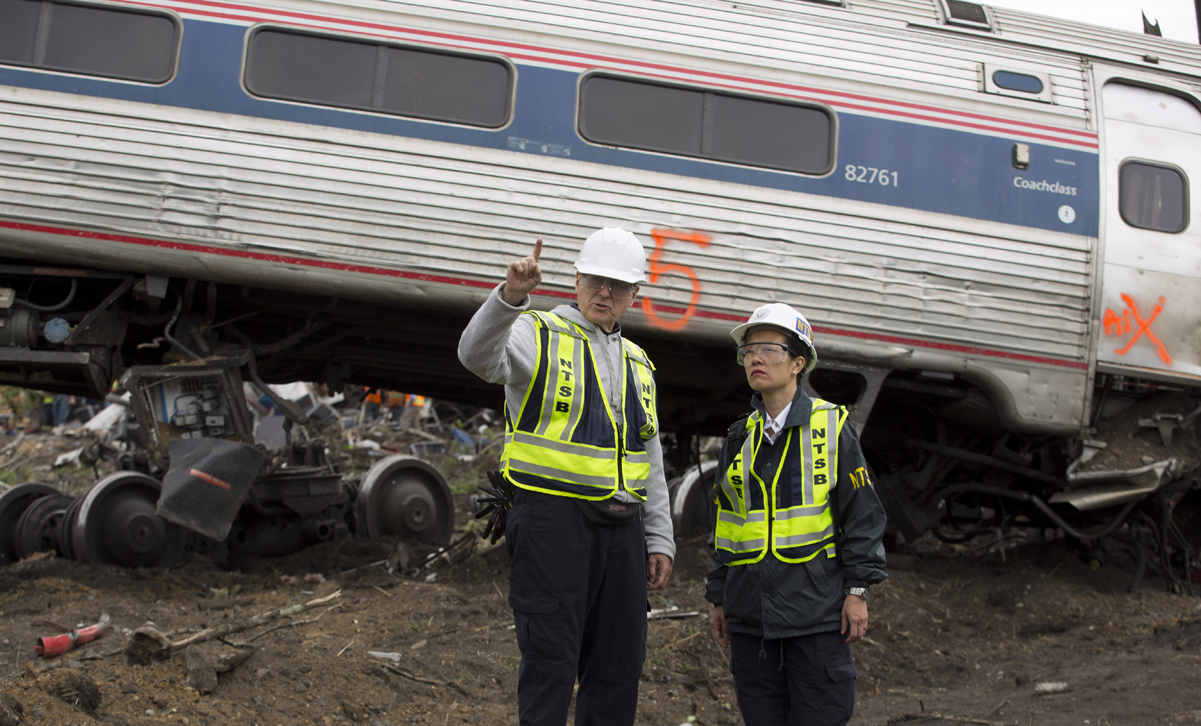 Men standing in front of derailed passenger car