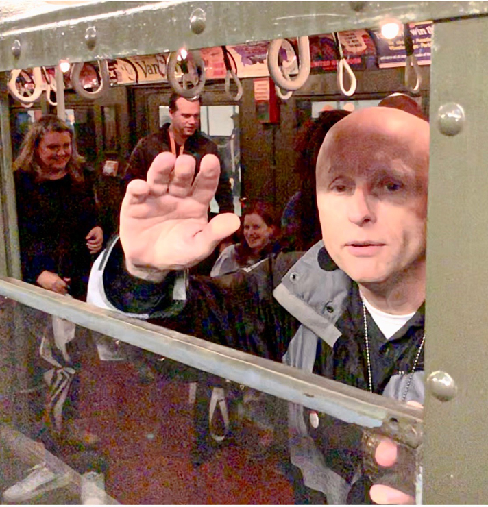 Man waving from window of train car