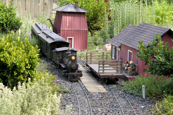 A steam engine rolling past a house on a garden layout