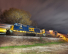 A train quickly moving by during sunset