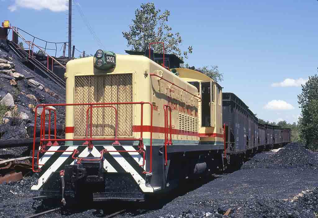Yellow diesel switcher locomotive surrounded by coal