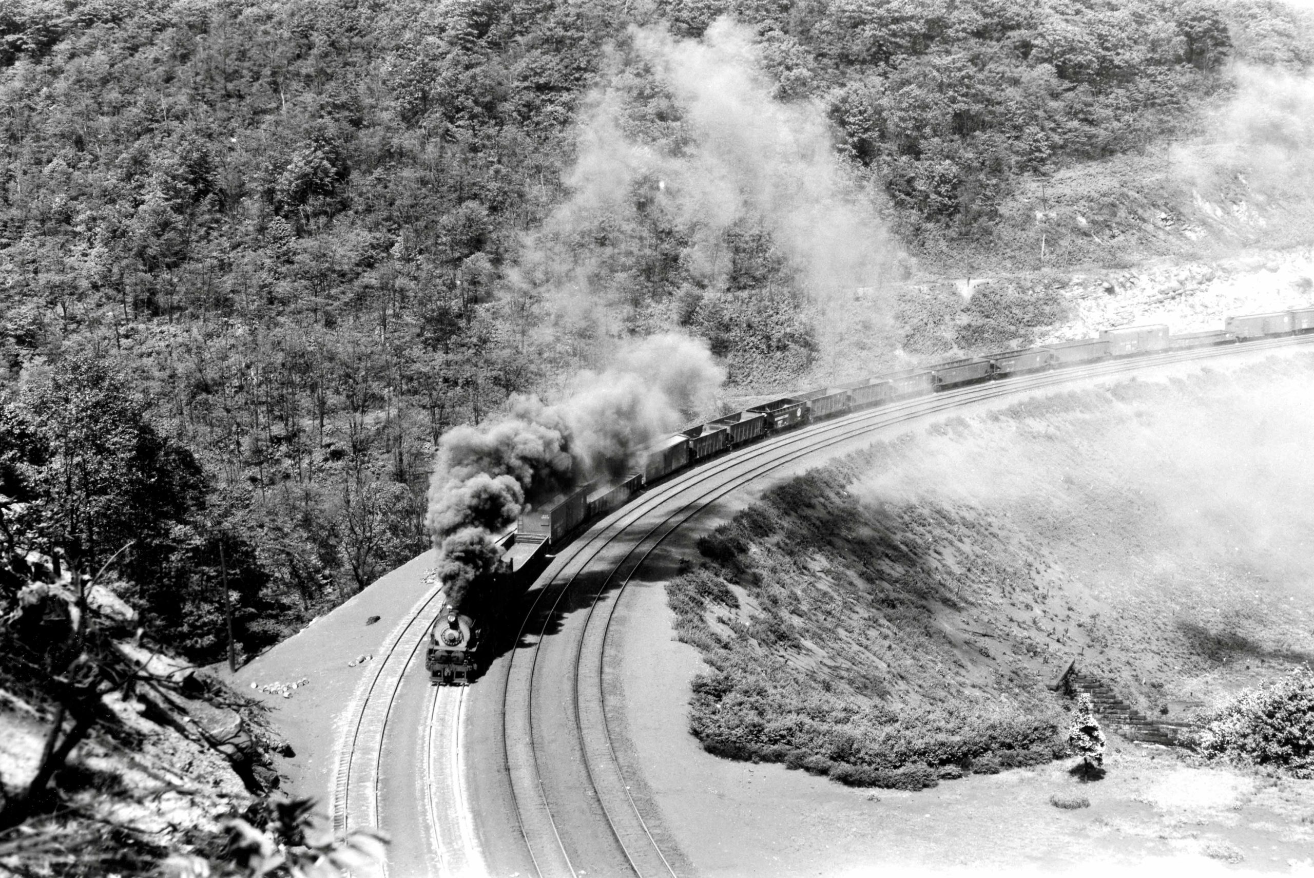 Pennsylvania Railroad class I1s 2-10-0 Decapod steam locomotive works its way around famous Horseshoe Curve with a westbound freight train in the 1940s. The train is ascending Allegheny Mountain 5 miles west of Altoona, Pennsylvania, location of the PRR’s system shops. 