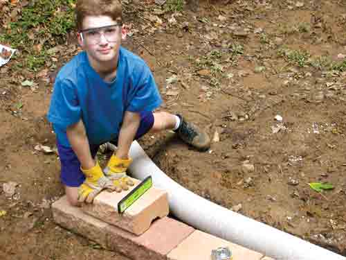 boy laying block on retaining wall