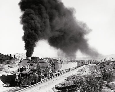 Steam locomotive with diesels and freight train. Black and white photo