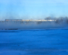 A distant shot of a train traveling over a snowy and icy bridge