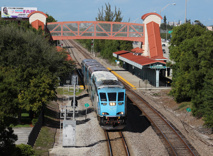 Light blue commuter train departs from station 