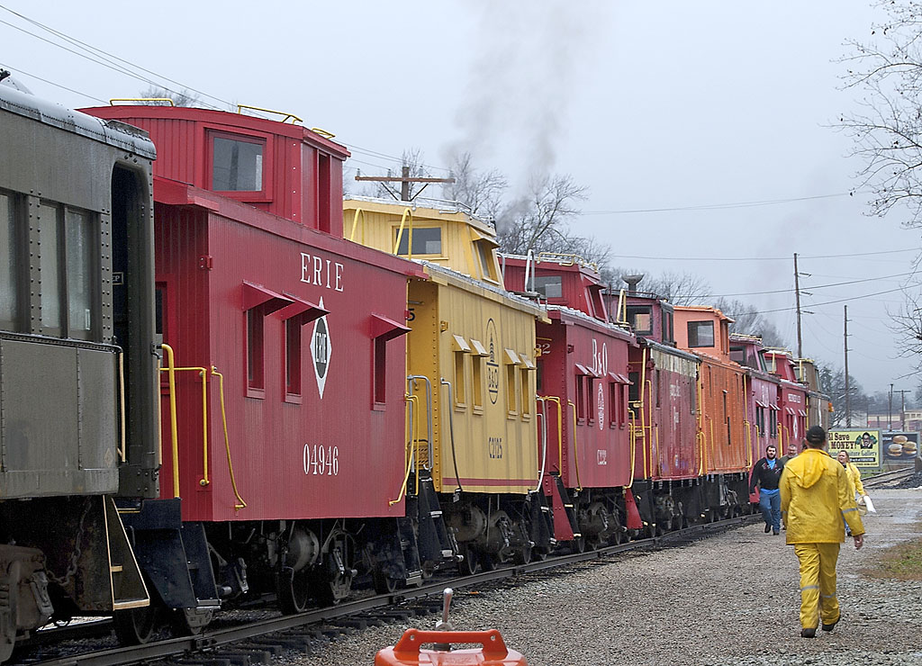 A line of colorful cabooses sits behind a gravel loading platform