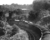A black and white picture from behind and above a locomotive as it turns the corner