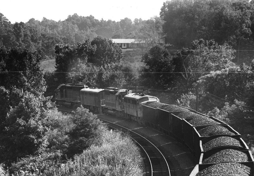 A black and white picture from behind and above a locomotive as it turns the corner