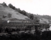 A black and white photo of locomotive No. 97 moving on the tracks past some water