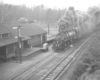 A black and white photo of 4-6-6-4 Challenger 652 moving pass a station with smoke coming out of its chimney