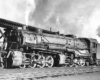 A train passing by with white smoke coming out of its chimney