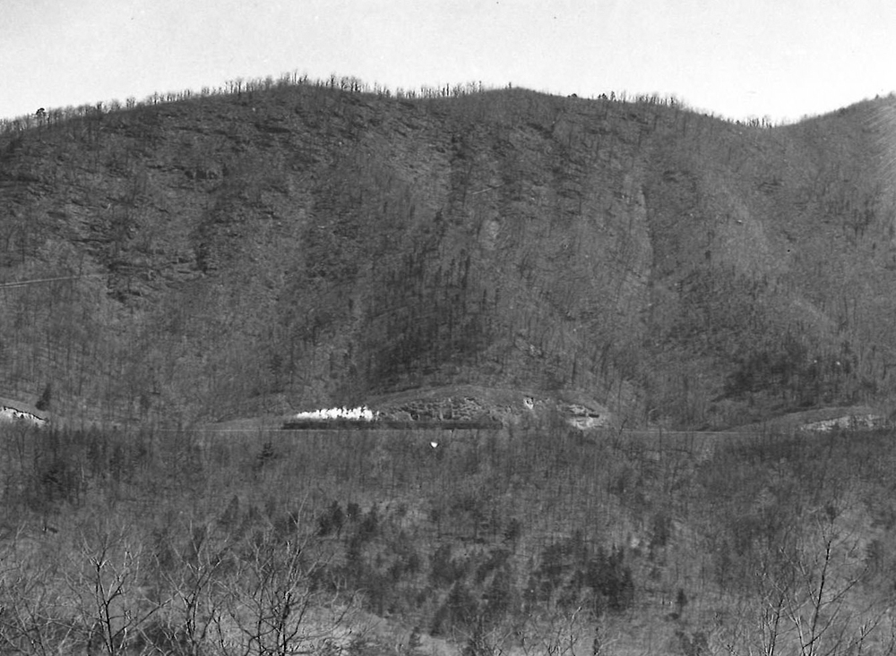 A far away black and white picture of Train 37 moving through the mountains