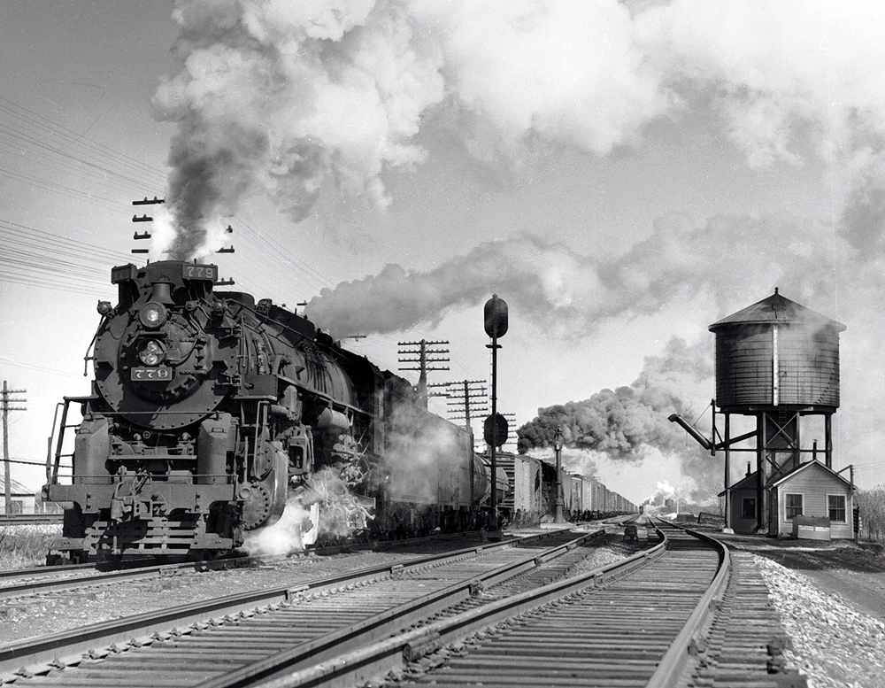 As an eastbound clears in the distance, Nickel Plate 779, Lima’s last 2-8-4, and a sister placed five cars back because of bridge weight restrictions, leave NH Tower near North East, Pa., in March 1957. 