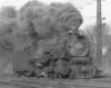 A close up black and white photo of a L1s 2-8-2 Mikado steam locomotive coming down the tracks with big black smoke coming out of its chimney