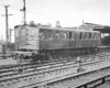 A black and white photo of a D1 third-rail electric locomotive outside a station