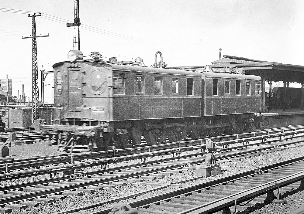 A black and white photo of a D1 third-rail electric locomotive outside a station