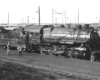 A black and white photo of a H9 2-8-0 Consolidation No. 3529 locomotive in a rail yard with two people talking next to it