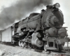 A black and white close up photo of a 2-10-0 steam locomotive with some smoke coming out of its chimney