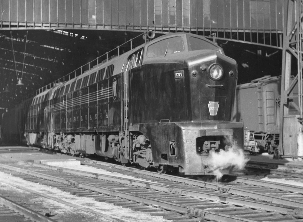 A black and white photo of a locomotive leaving a station