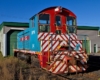 A red and white train parked outside an enginehouse