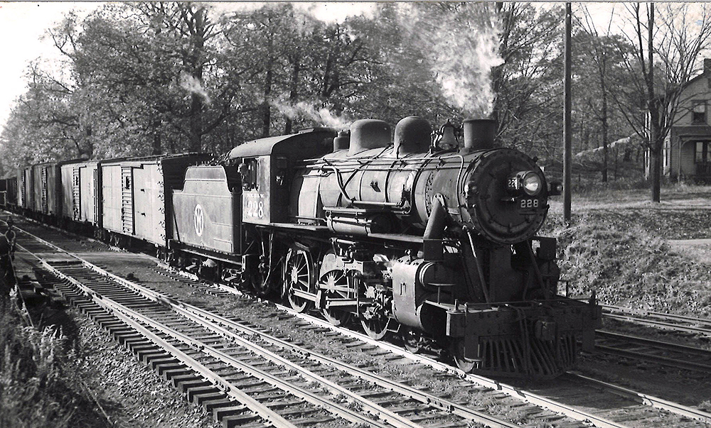 Steam locomotive with freight train passing house