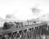 Steam locomotive with freight train on deck-truss bridge