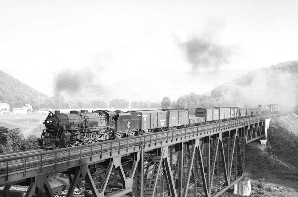 Steam locomotive with freight train on deck-truss bridge