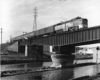Diesel locomotive with four-car passenger train on bridge