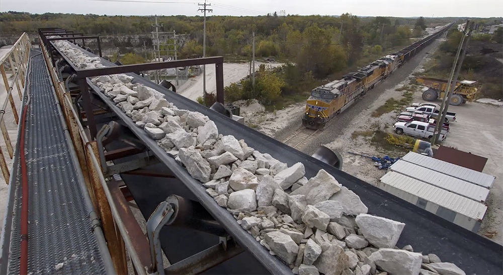 Close-up view of a rock-carrying conveyor belt in a rail-served quarry.