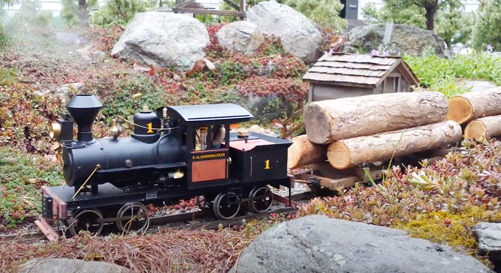 steam engine pulling flatcars with logs on a garden railroad