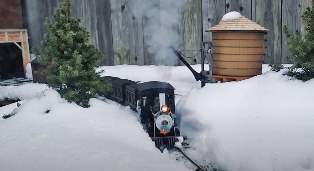 model train running on a snowy garden railway