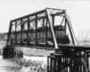 Three diesel locomotives with freight train on bridge in snow