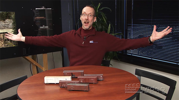David Popp sitting at a table with various freight cars.
