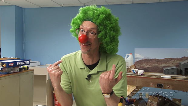 David Popp wearing a clown nose and a green wig introducing a video in the Model Railroader workshop.