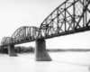 Steam-powered passenger train on large truss bridge over water