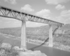 Deck truss bridge with concrete piers over canyon