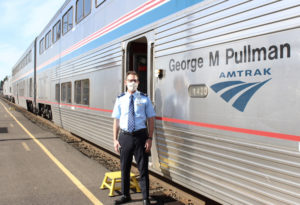 Man in Amtrak uniform standing next to the George M. Pullman car