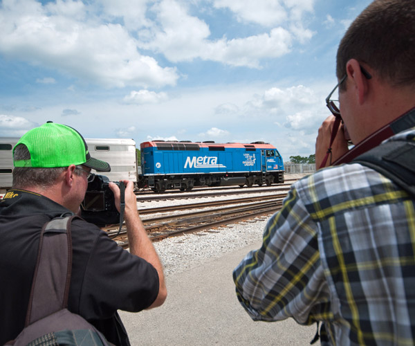 Two men filming blue train